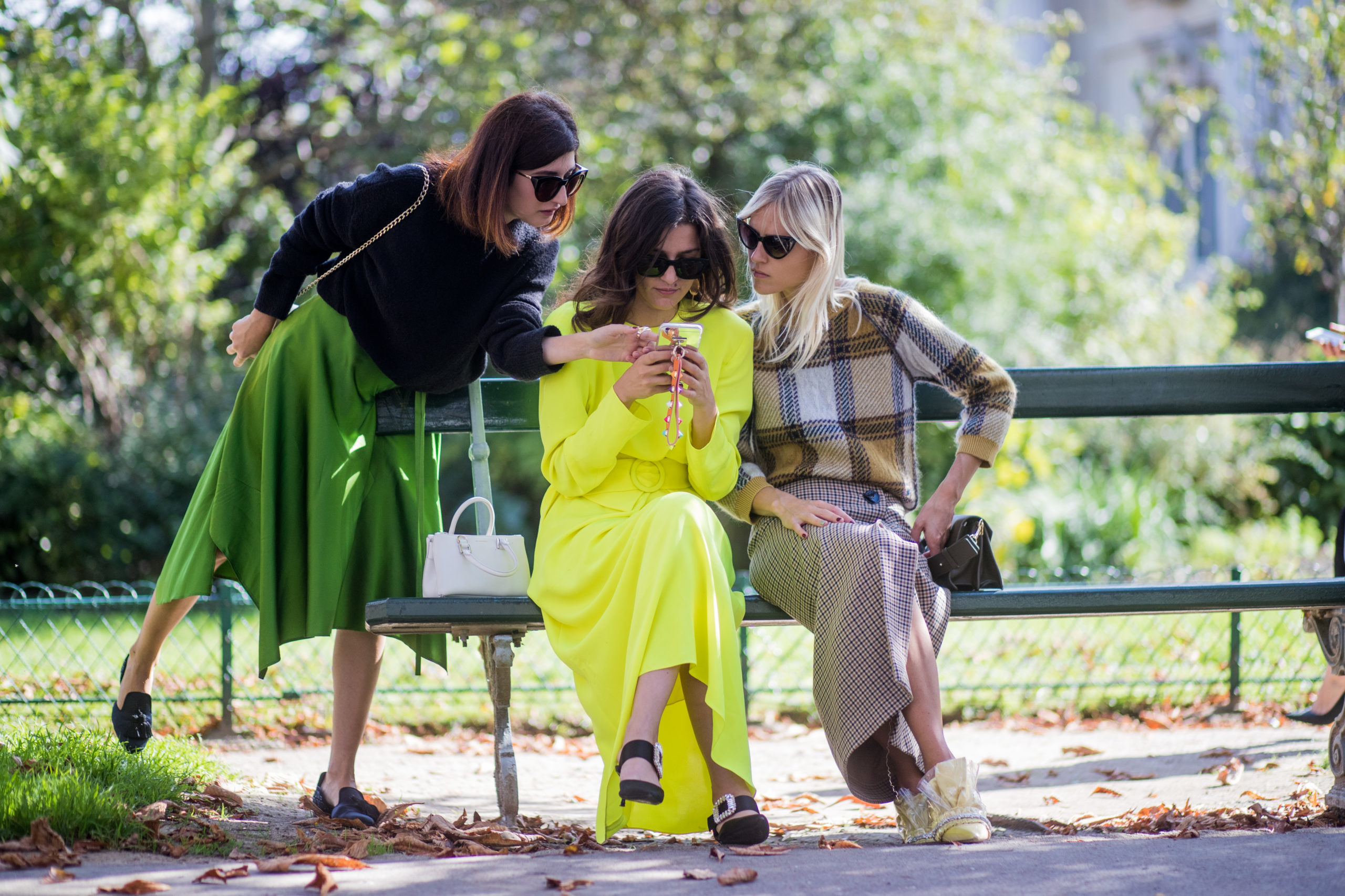 PARIS, FRANCE - SEPTEMBER 29: Valentina Siragusa and Eleonora Carisi wearing neon dress and Linda Tol sitting on a bench looking at a mobile phone seen outside Issey Miyake during Paris Fashion Week Spring/Summer 2018 on September 29, 2017 in Paris, France. (Photo by Christian Vierig/Getty Images)